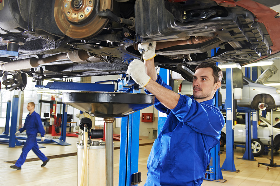 Certified professional mechanic working on a raised vehicle in a Buick and GMC Service Center